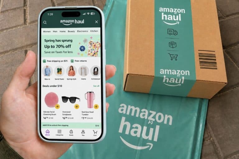 A hand holding a phone displaying the Amazon shopping app, with an Amazon package and branded bag on a stone surface in the background—perfect for scoring Amazon deals or showcasing your latest Amazon haul.